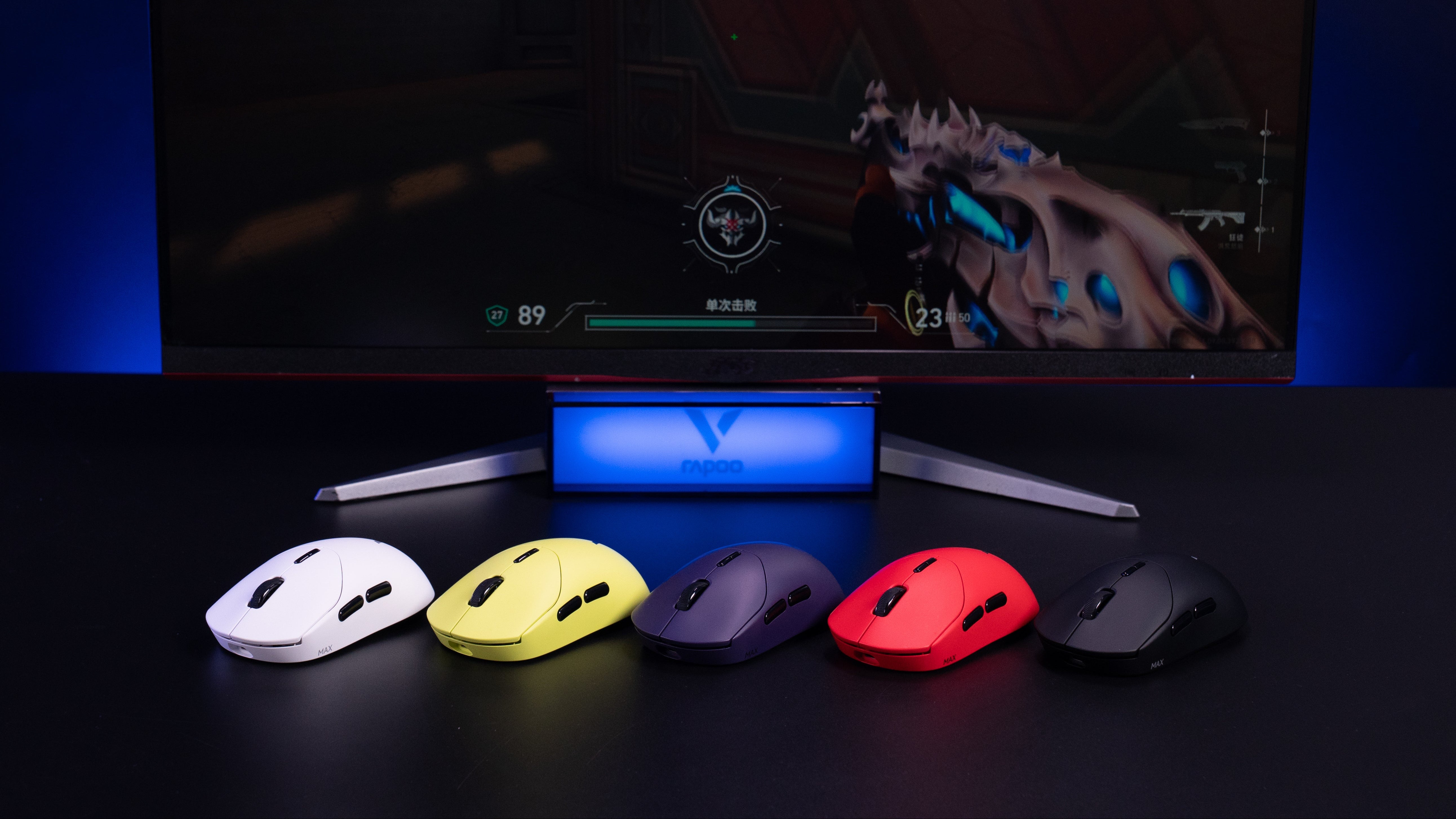Five colorful gaming mice in front of a monitor displaying a game.